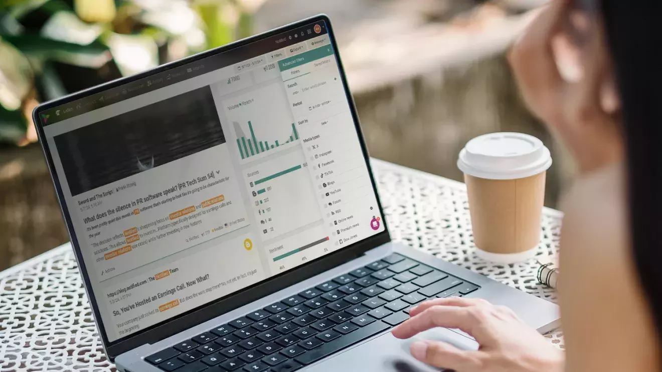 Woman using Notified's social listening dashboard in a coffee shop