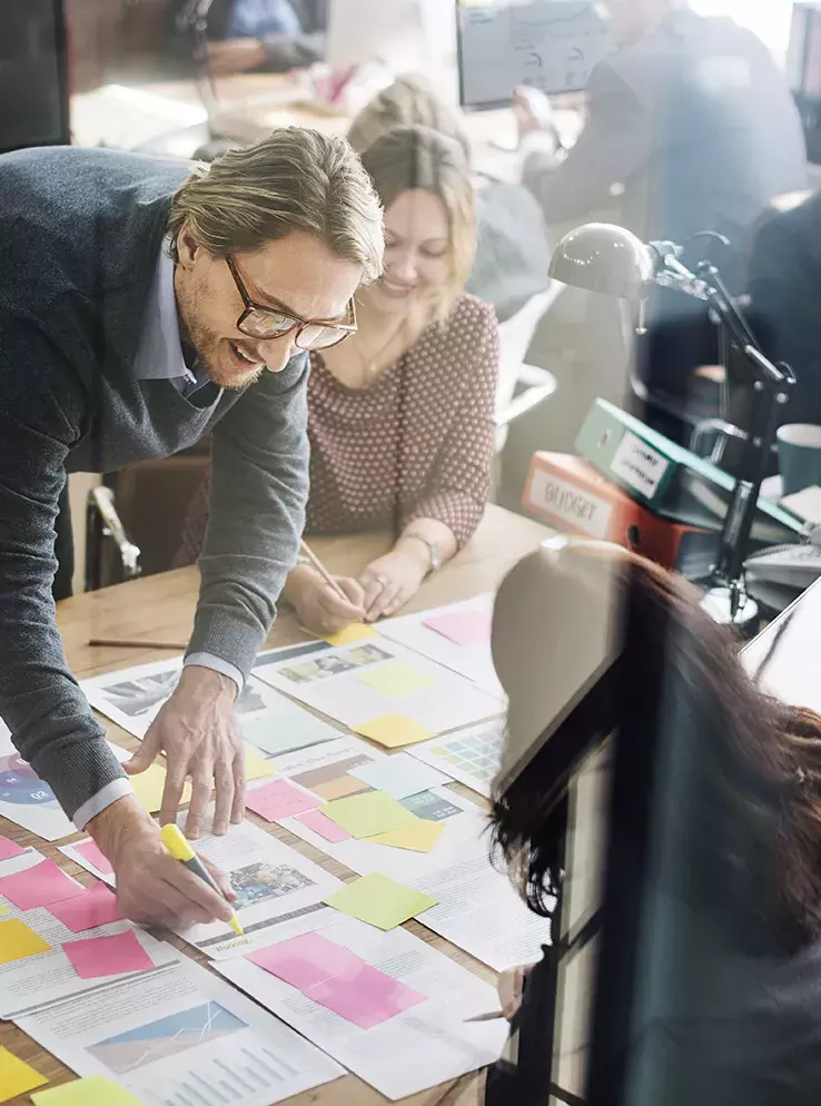 Well-dressed man highlighting papers spread out on a conference table